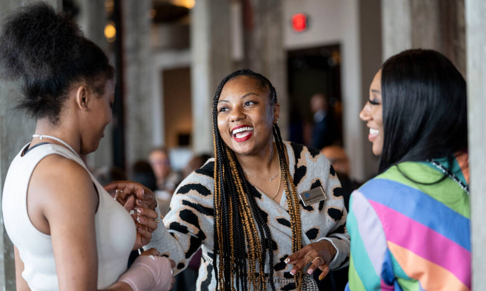 Three women laughing while attending a School Celebration and Social event in Detroit.
